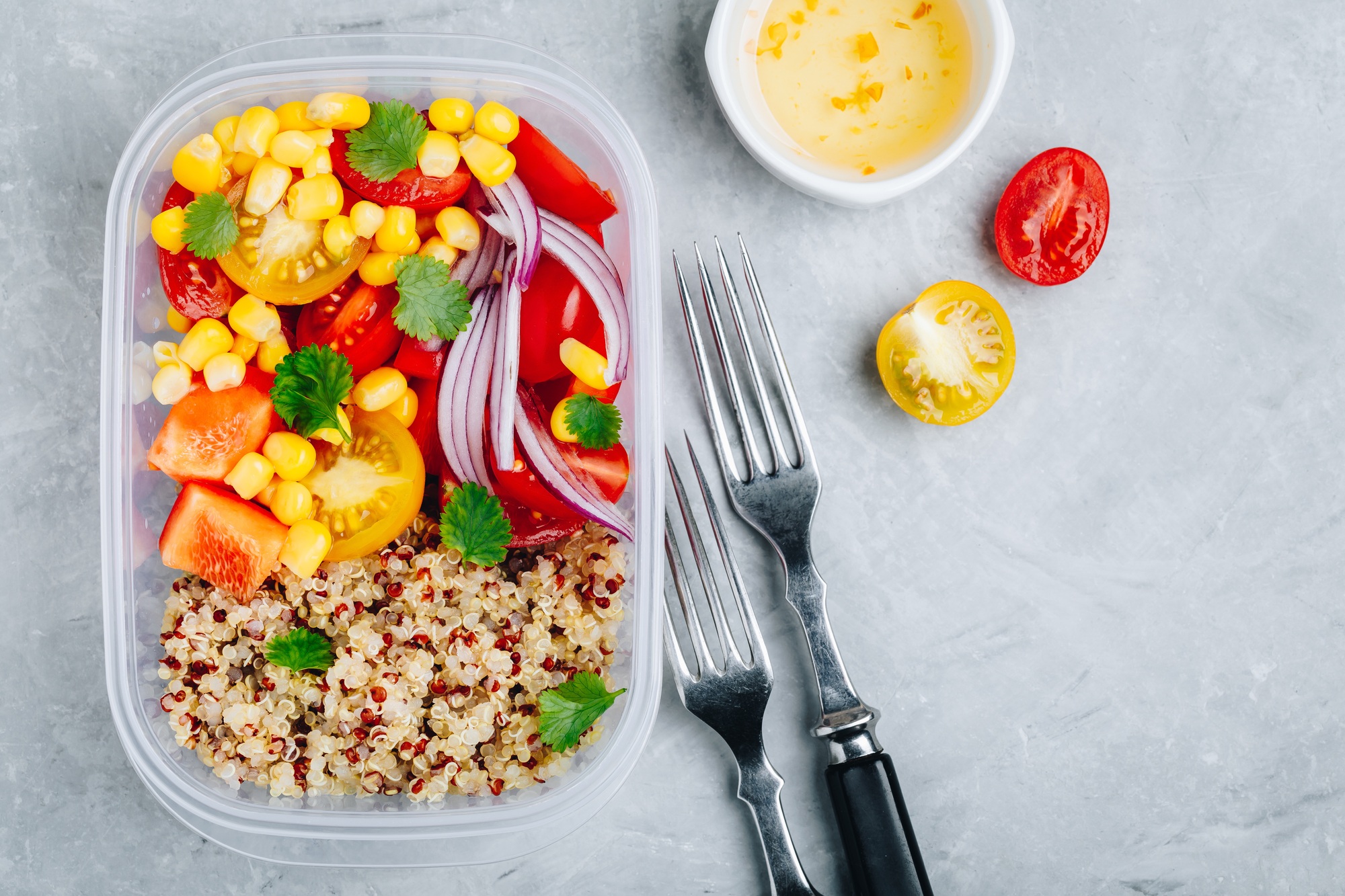 Healthy vegan meal prep containers with quinoa and fresh vegetables